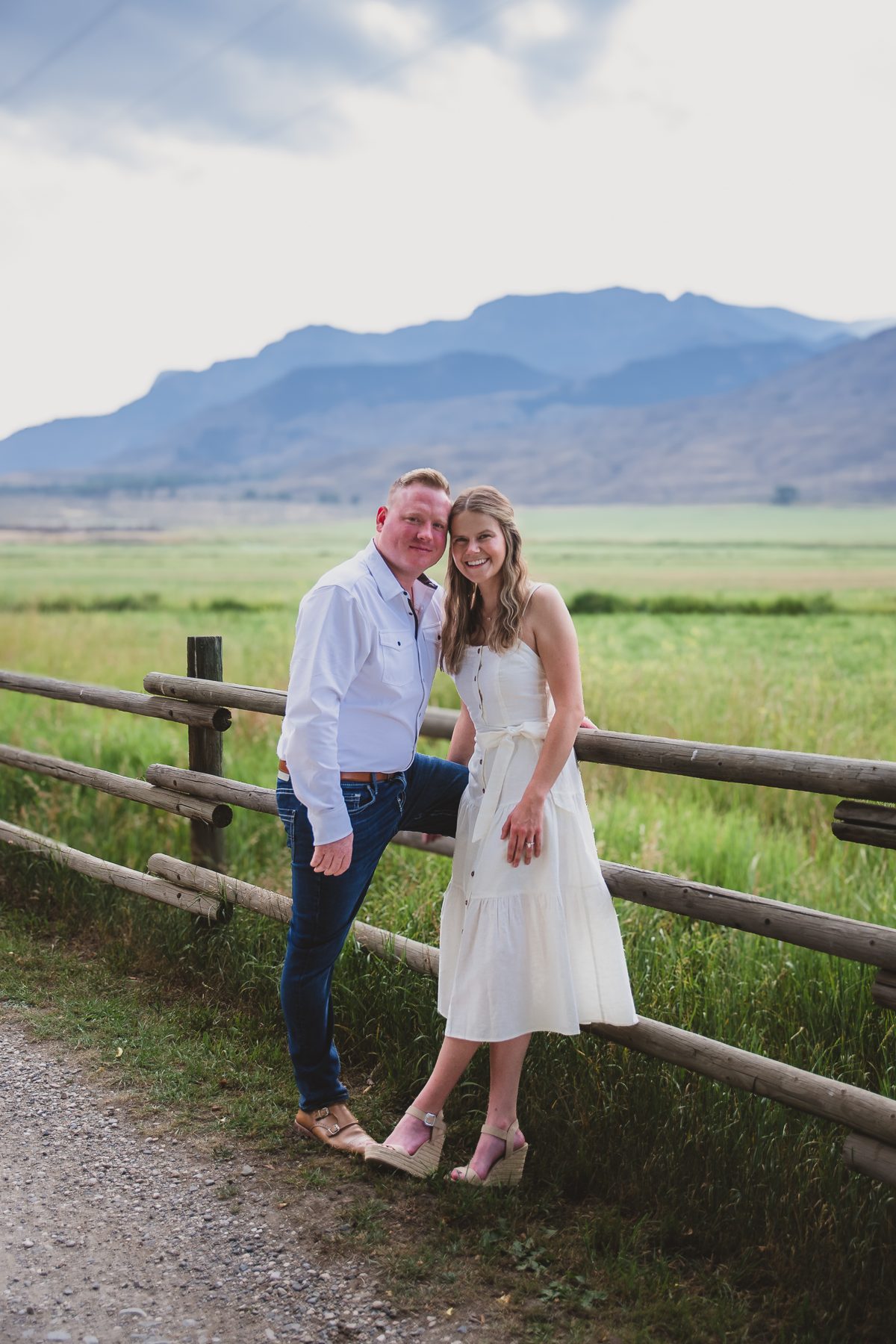 Mariah and Gabe at the fence under a big mountain sky